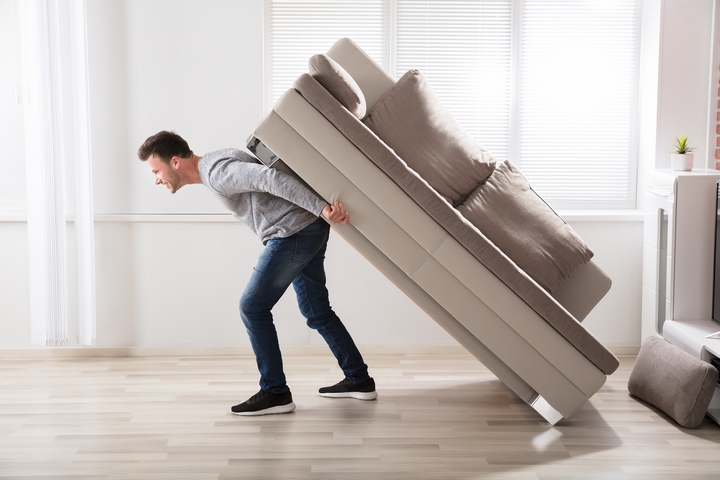 Man lifting a heavy couch on his own