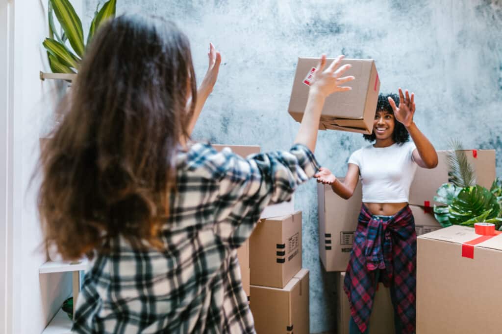 Woman throwing moving box to friend