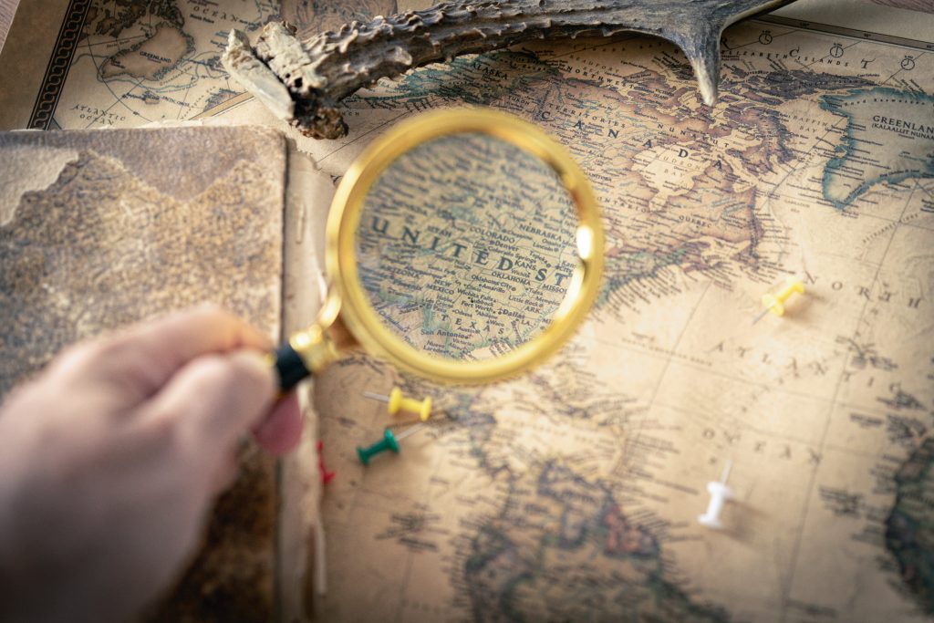 A person holding a magnifying glass over a map of the United States