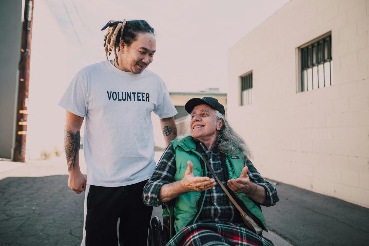 A volunteer providing support to a man in a wheelchair