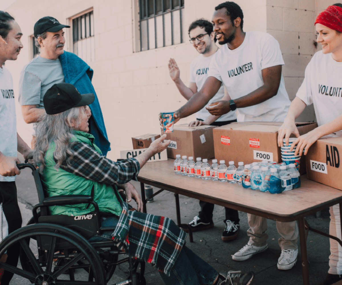 Volunteers at a food drive handing supplies to a man in a wheelchair