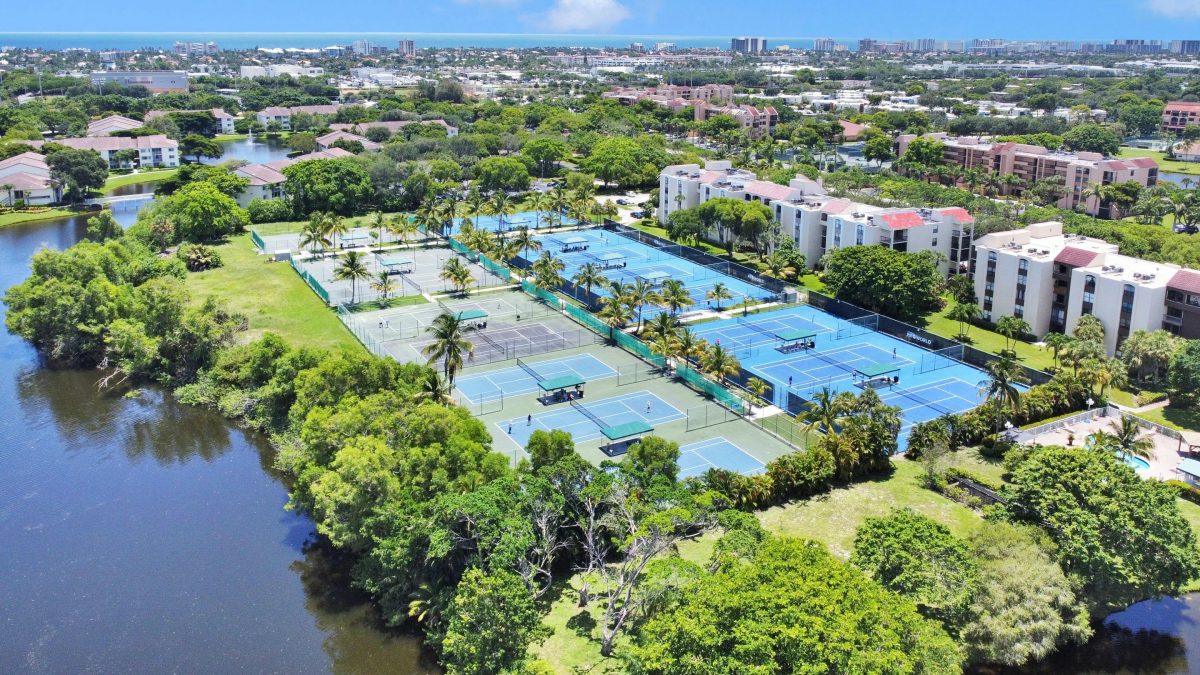 Tennis courts surrounded by green trees near body of water in Boca Raton, Florida