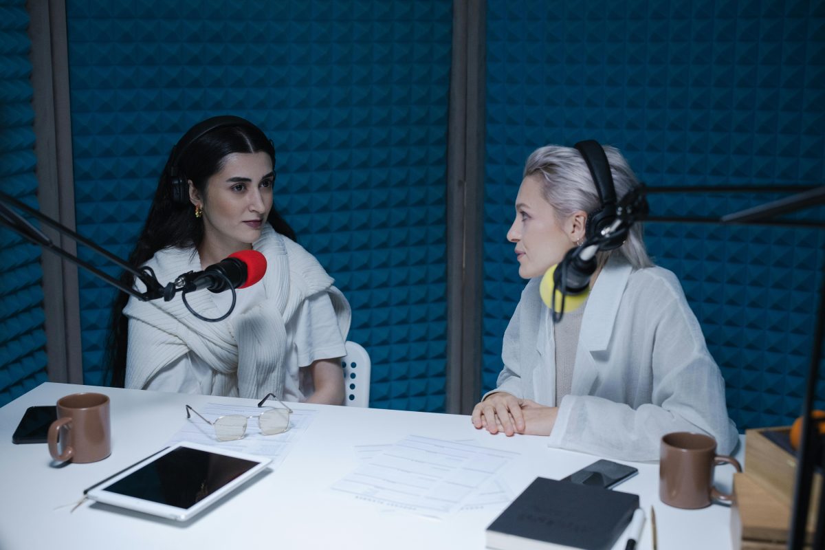 Women in soundproof office having conversation while wearing headphones