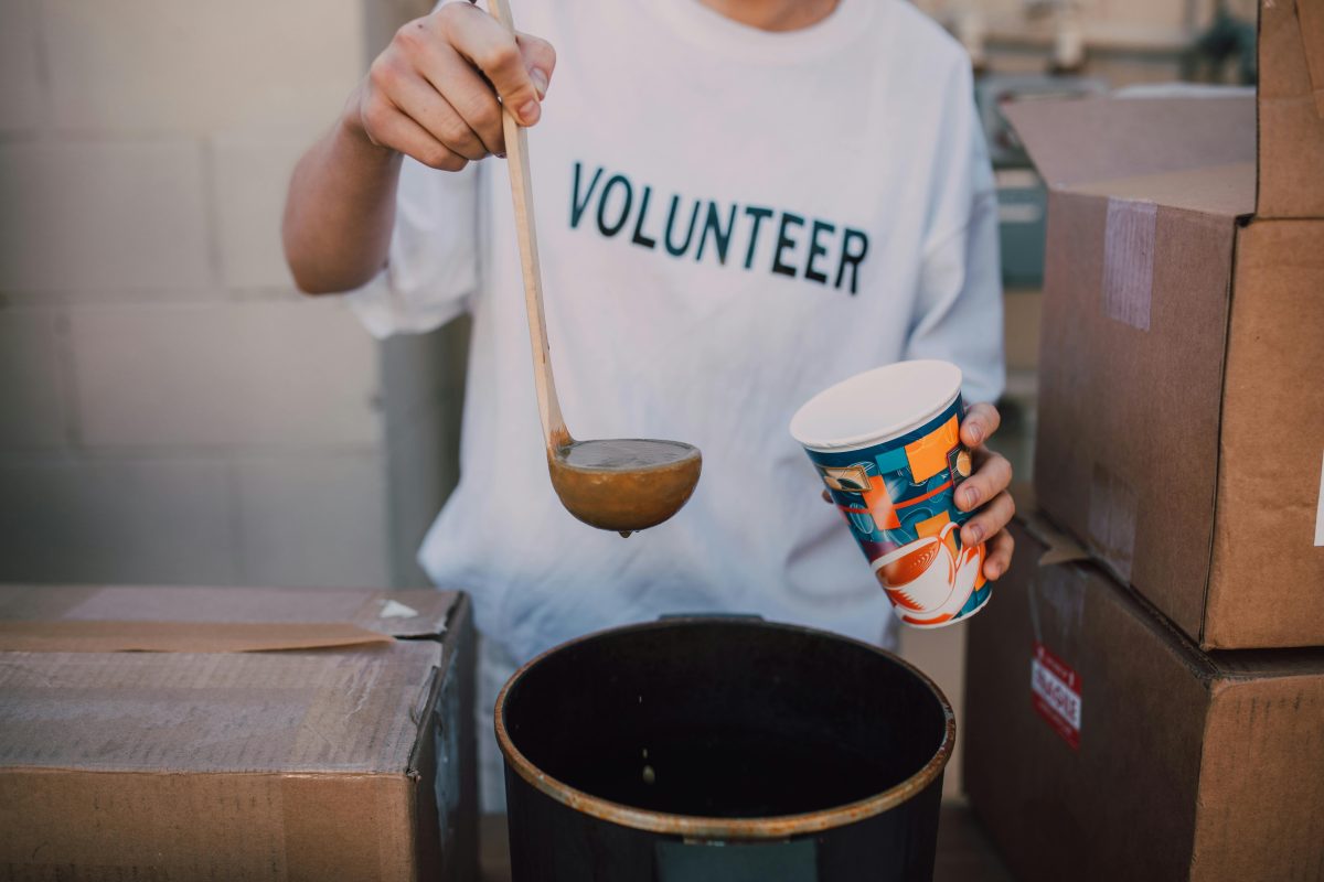 A volunteer scooping soup with a ladle