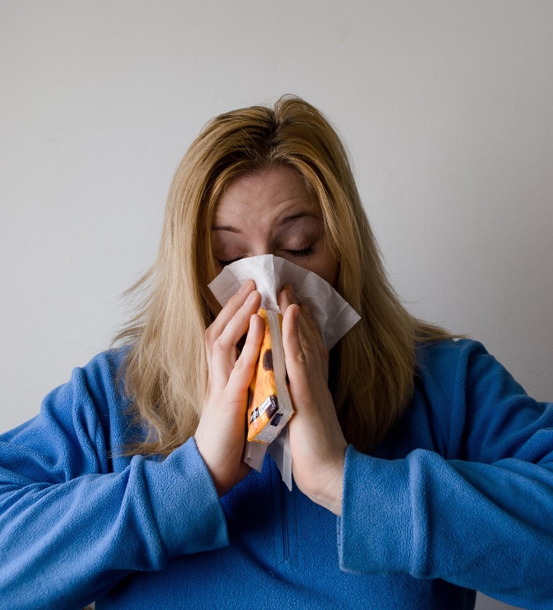 A woman sneezing into a tissue