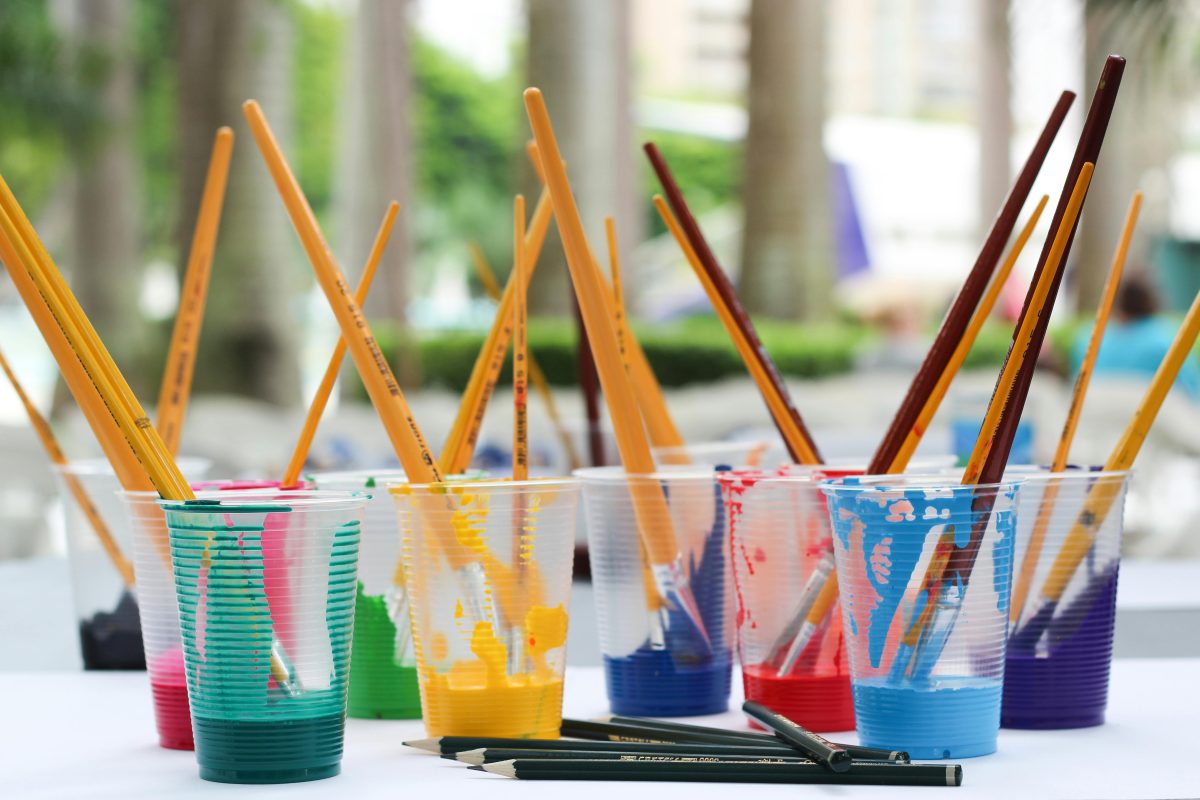 Pain brushes inside plastic cups holding paints
