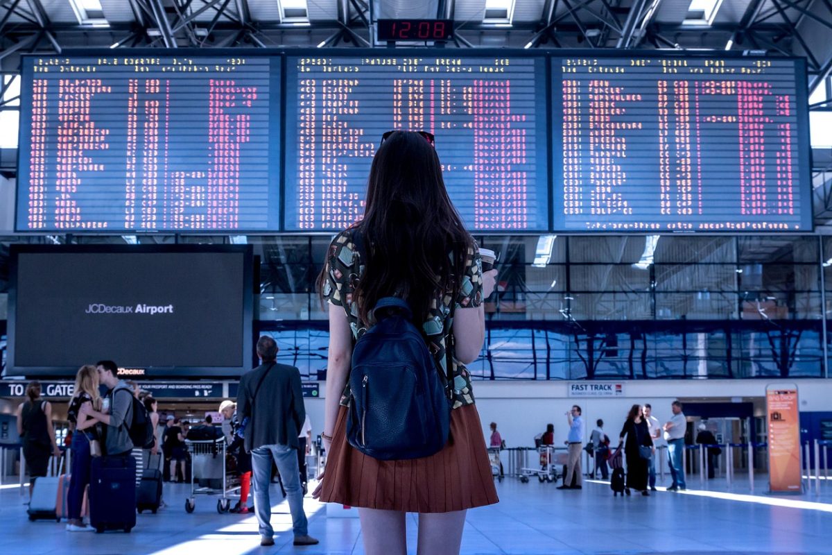 A woman in the airport looking at flight listings on an LED screen