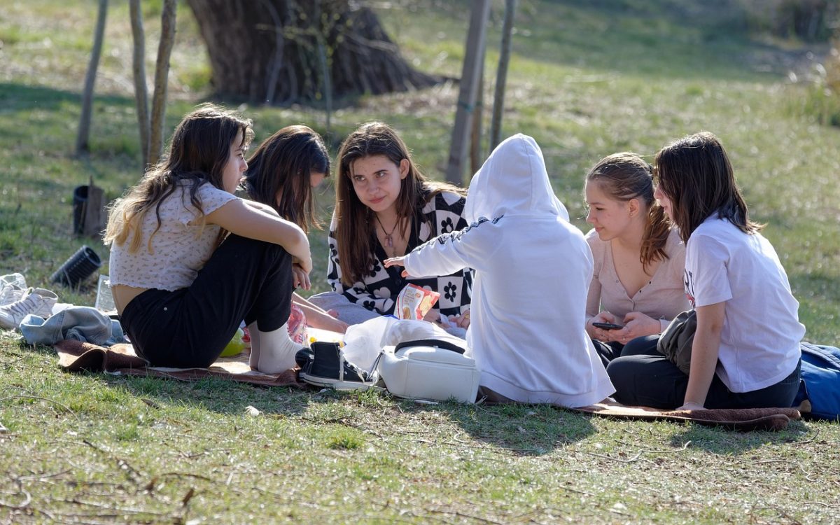 A group of girls sitting in a circle and talking in a field