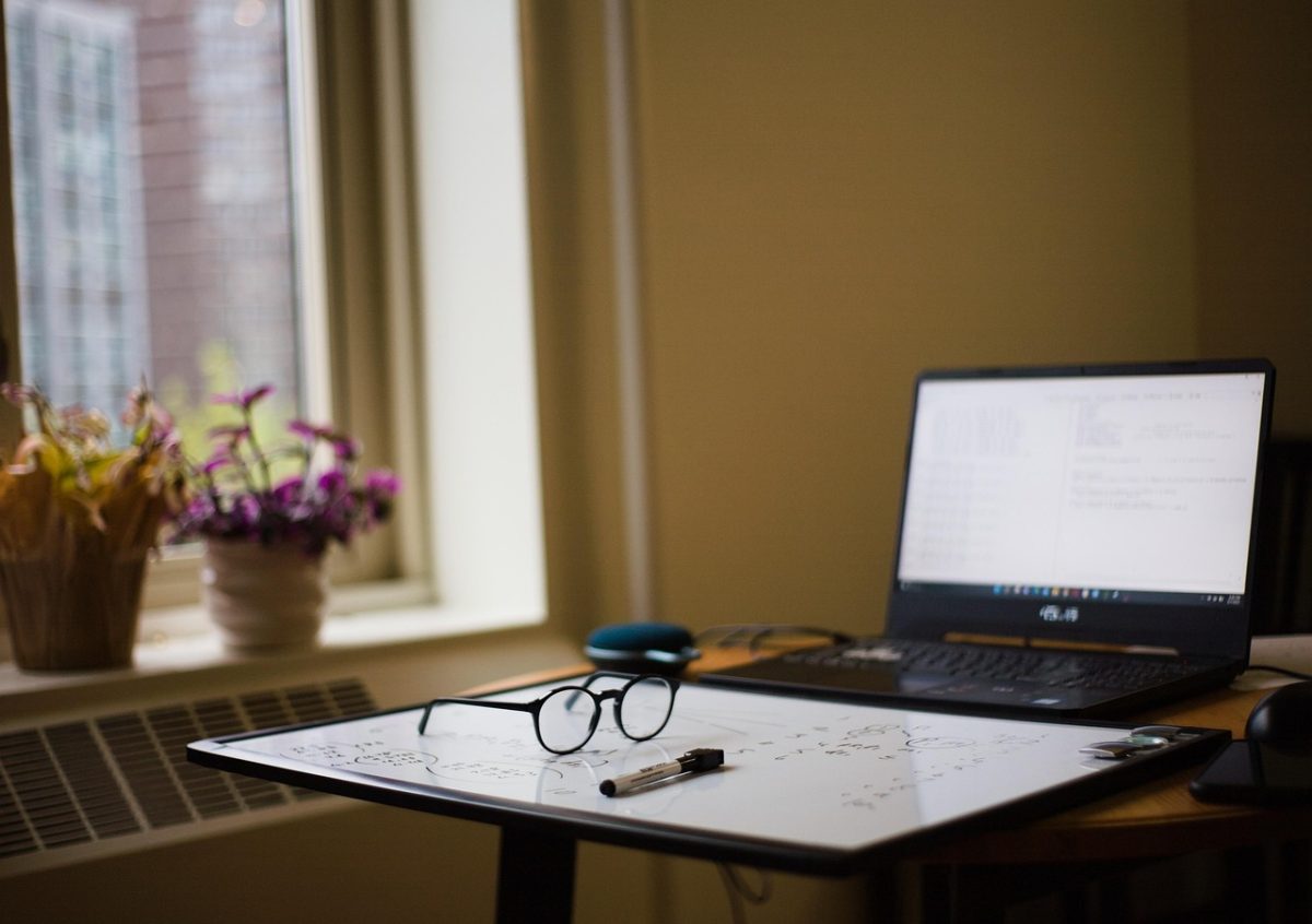 A work desk with a laptop and a white board