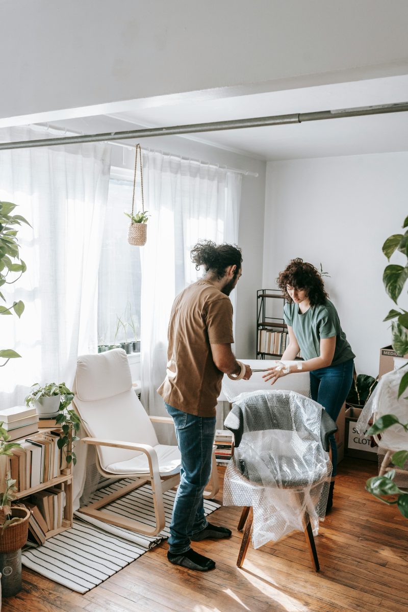 Couple wrapping a chair to protect their house while moving