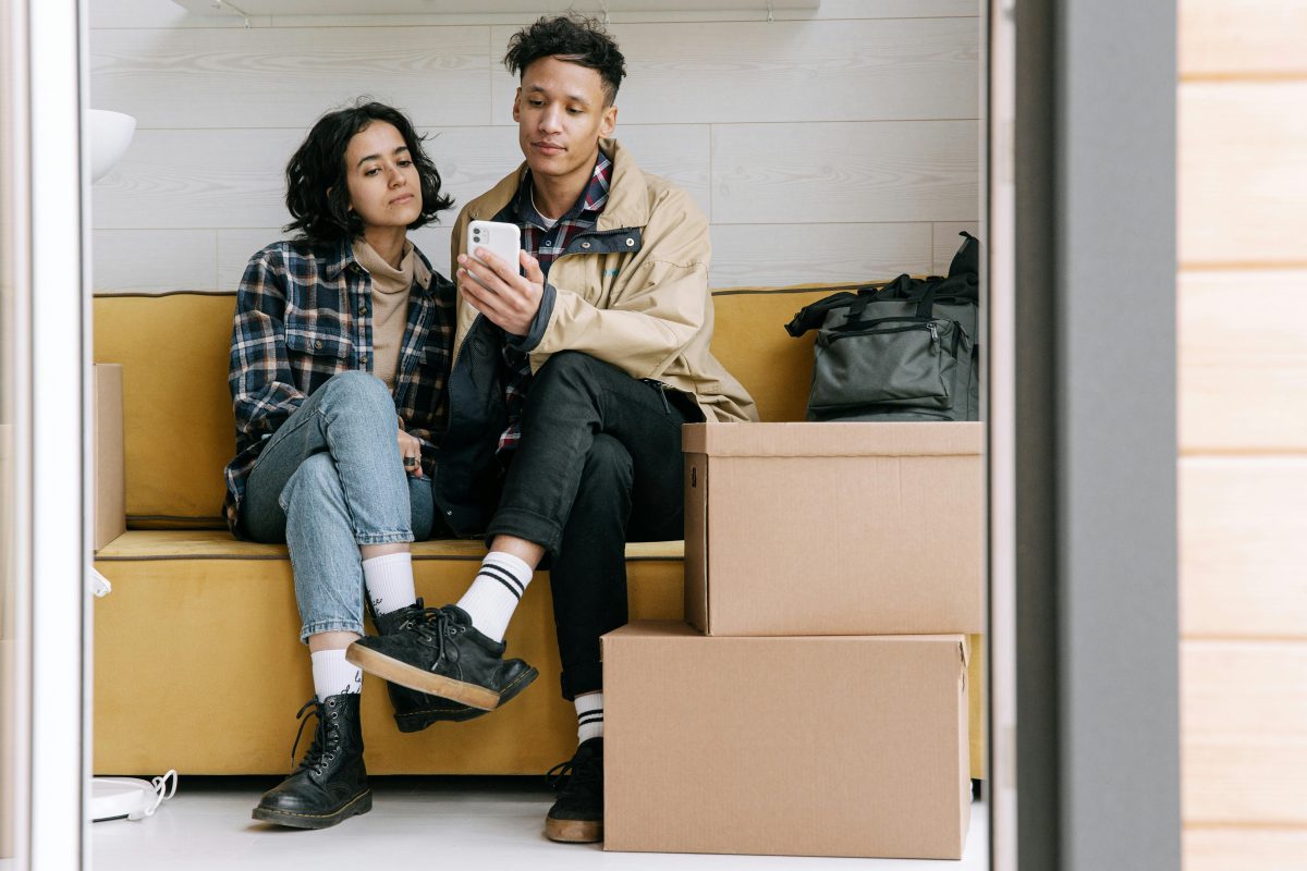 Couple sitting on yellow couch and looking at smartphone