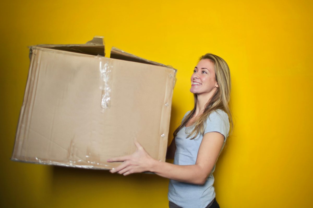 Woman in grey shirt holding brown cardboard box