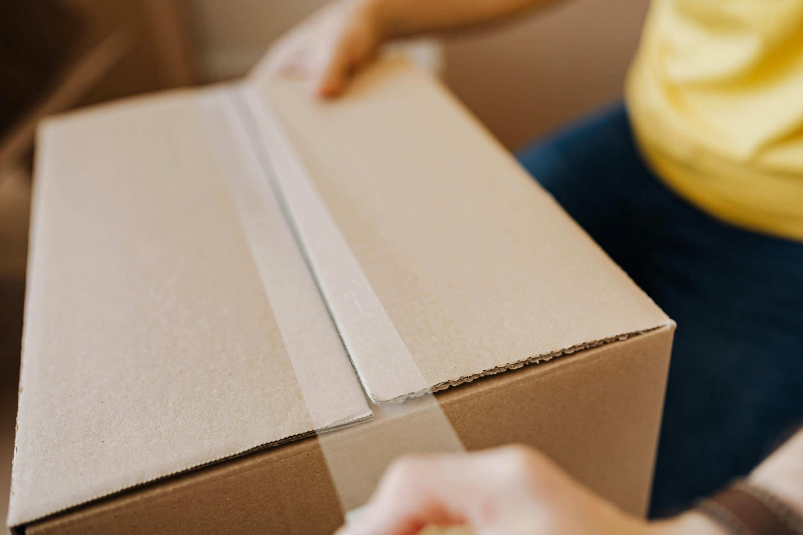 Man sealing cardboard box with tape