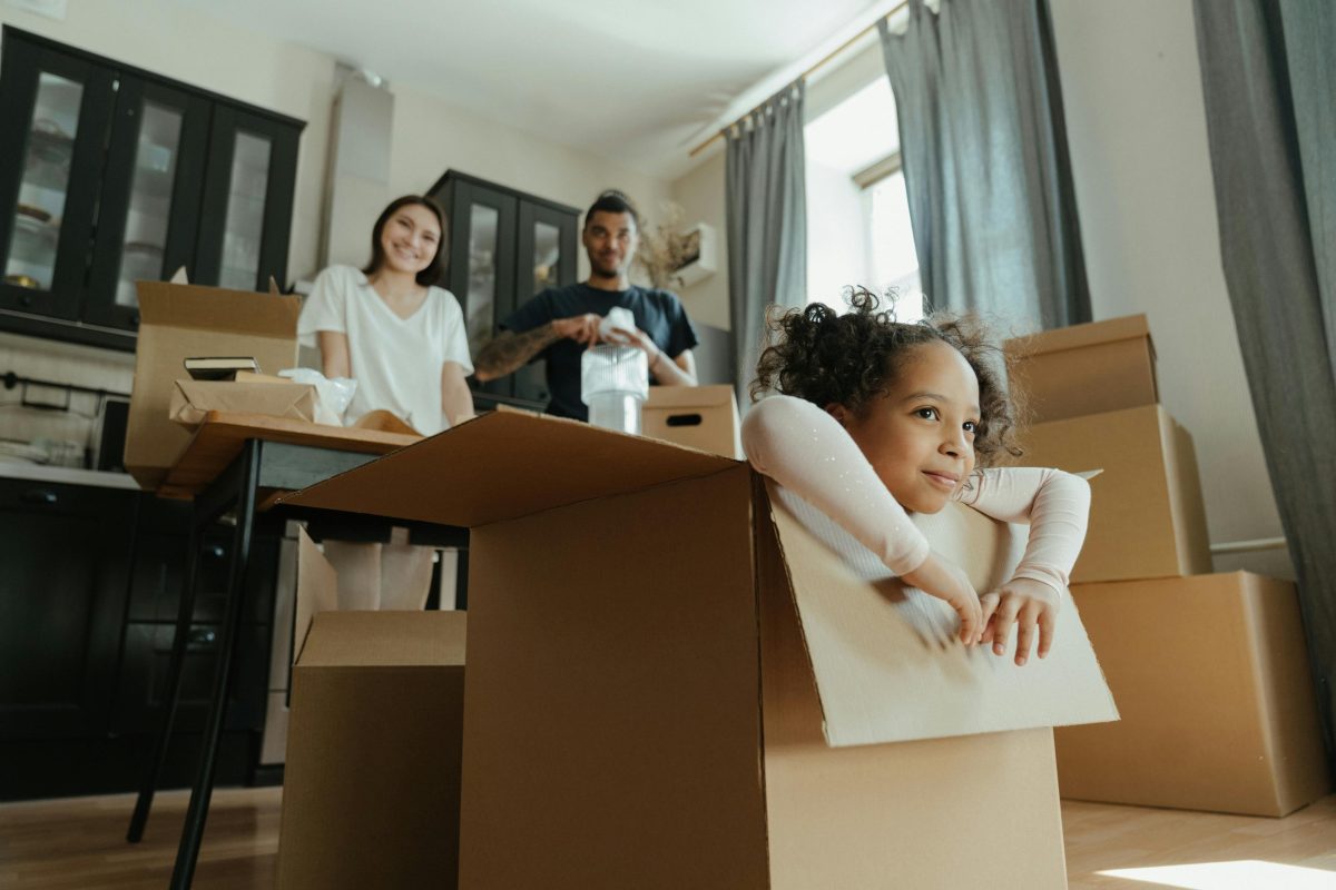 Little girl playing in a moving box while parents watch