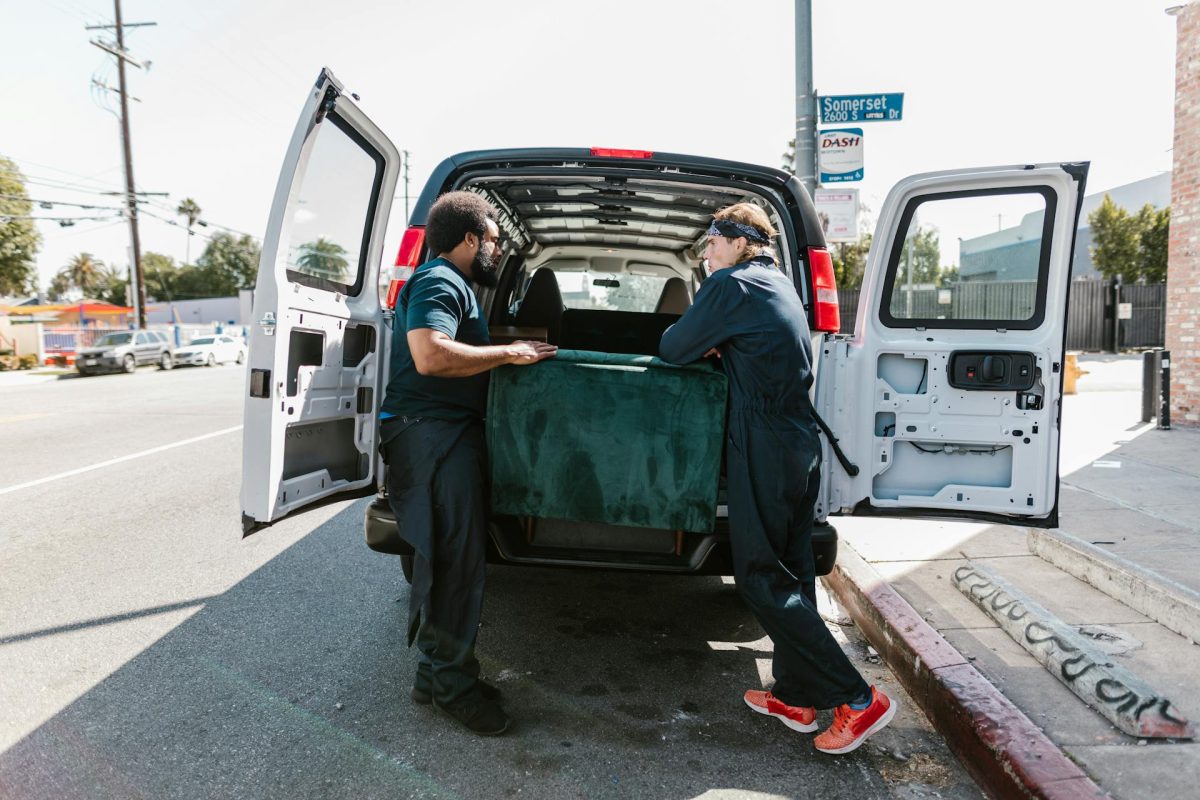 Two men loading a couch into the back of a van