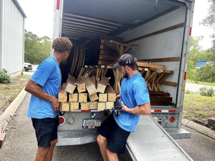 Labor-only movers unloading lumber from a moving truck